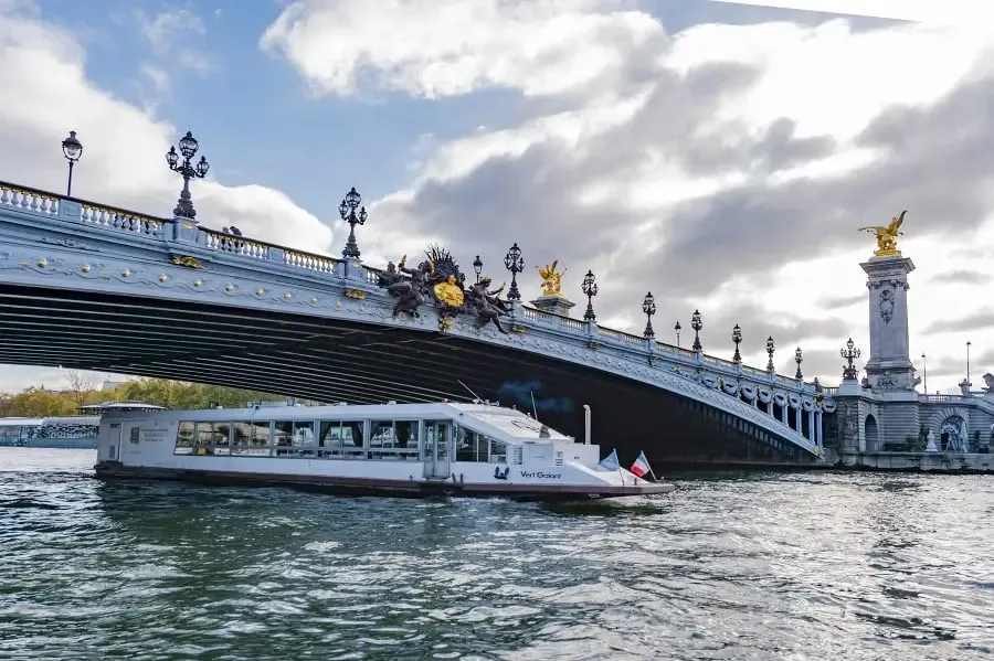 Barco de Paris Seine navegando de noche frente a la Torre Eiffel iluminada