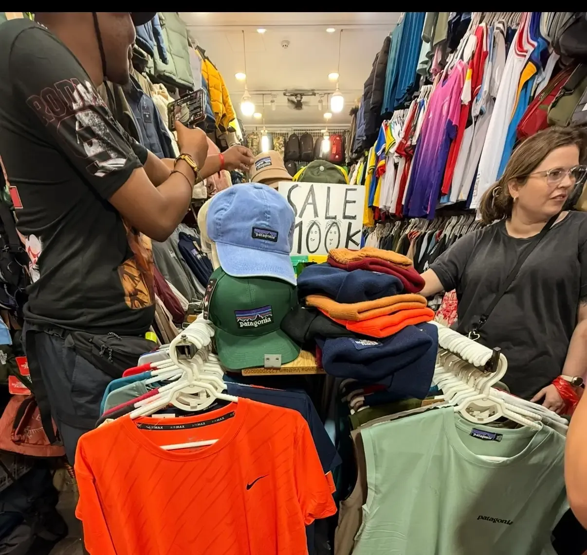 Étal de vêtements dans un marché nocturne vietnamien avec des vêtements de sport et des sacs à dos