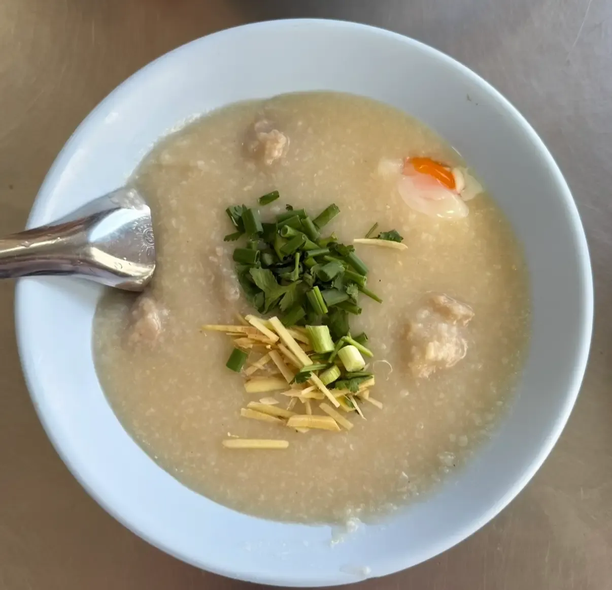 Un bol de Congee thaïlandais (Jok) servi avec un œuf et des boulettes de porc